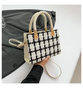 Sac à main en tweed à carreaux noir et blanc avec poignées tressées et bandoulière.