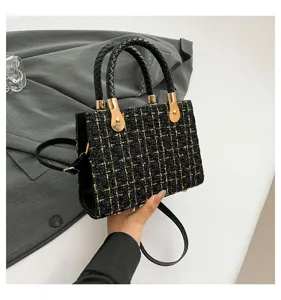 Sac à main en tweed noir et or doté de poignées tressées et d'une bandoulière élégante.