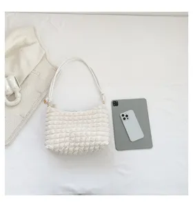 Detail view of white pleated shoulder bag with soft textured fabric and slim strap design.