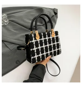 Sac à main élégant en tweed noir et blanc avec motif pied-de-poule et détails dorés raffinés.