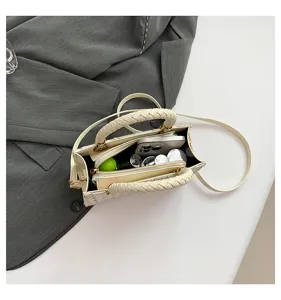 Vue détaillée du sac bandoulière en tweed avec poignée tressée et compartiment.