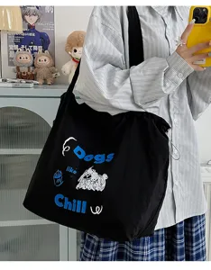 Close-up detail of casual black canvas tote bag, featuring cute doodle dog print and letters.