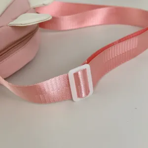 Pink bag strap detail with white adjuster buckle and cute bunny ear design closeup view.