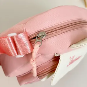 Pink canvas crossbody bag detail showing zipper, adjustable strap, and cute flap design.
