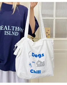 Close-up detail of white canvas tote bag with stylish blue letter embroidery and cute dog print.