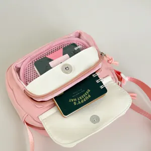 Detailed view of pink crossbody bag multi-compartment front pockets and smooth zippers.