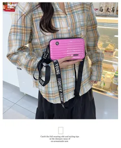 Mini pink suitcase crossbody bag for women, stylish hard-shell shoulder handbag.