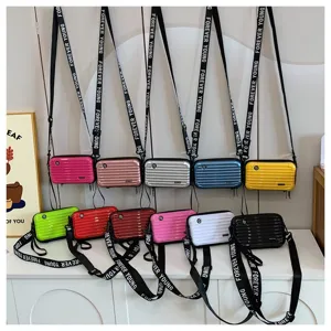 Mini suitcase style crossbody bag detail showing multiple colors and letter strap design