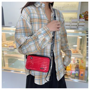 Mini hard shell suitcase crossbody bag detail, unique red design with strap for women fashion.