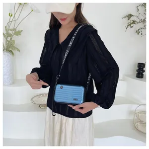 Mini blue suitcase style crossbody bag detail view with black letter strap worn by model