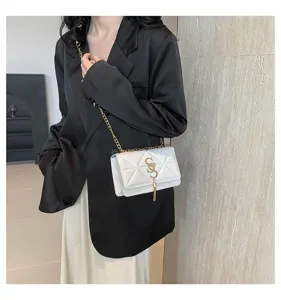Detailed view of white quilted chain crossbody bag with stylish gold metal hardware accent.