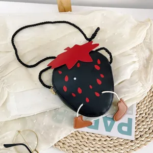 Close-up detail of the cute black strawberry crossbody bag with little brown boots and red seeds.