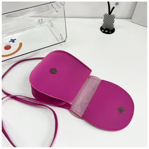 Detailed close-up view of pink mini crossbody bag featuring snap button closure and strap.