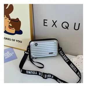 Mini silver suitcase crossbody bag hard shell shoulder bag with stylish strap for women.
