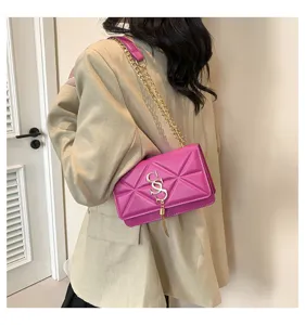 Detail shot of a fuchsia quilted shoulder bag with gold chain strap and metal clasp.