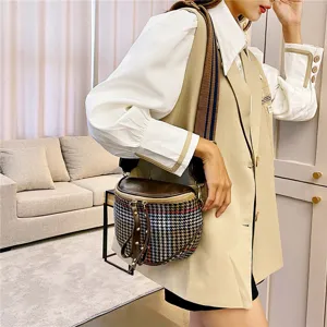 Detailed shot of the chic houndstooth crossbody bag featuring a wide strap and tassels.