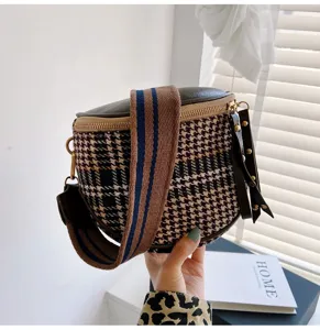 Detailed close-up view of the stylish houndstooth crossbody bag with wide striped strap.