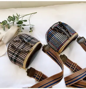 Detailed view of fashionable houndstooth crossbody bag with wide canvas strap and zipper.