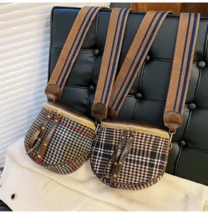 Detail view of the stylish houndstooth crossbody bag featuring wide striped straps and zippers.