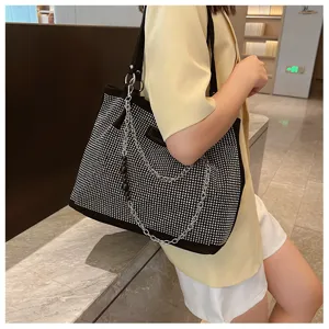 Detailopname van de zwarte tote-tas met strass-steentjes gedragen door een model.