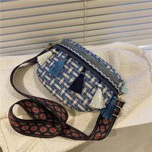 Detailansicht der gewebten Tweed-Umhängetasche mit bunten Quasten und breitem ethnischem Gurt.