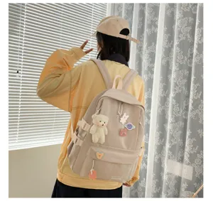 Detalle de mochila de lona, tierno colgante de oso, diseño multi-bolsillos para estudiantes.