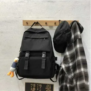 Detailed close-up view of Japanese style black utility backpack with dual buckles and duck charm.