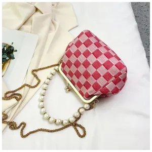 Detail view of the red checkered shell bag with chic pearl handle and gold chain.