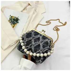 Denim kiss-lock cross-body bag detail featuring luxury pearl handle with gold chain strap.