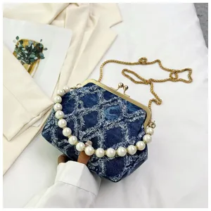 Detail view of stylish denim pearl handle handbag with metal kiss lock and shoulder chain.