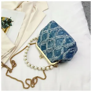 Detailed shot of a stylish denim kiss lock shoulder bag featuring a chic pearl handle and gold chain.