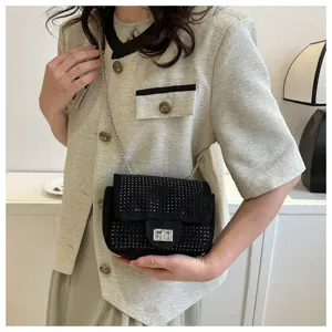 Detail view of the black rhinestone crossbody bag with metal chain strap and twist lock.