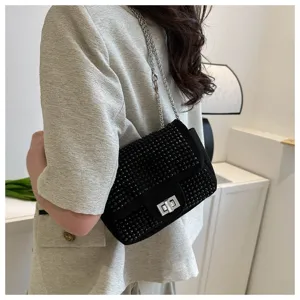 Detail shot of a black rhinestone crossbody bag with chain strap and chic metal lock closure.