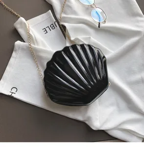 Vista dettagliata di una elegante borsa a tracolla nera in vernice a forma di conchiglia.