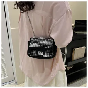Detail view of a black rhinestone flap crossbody bag worn by a model, shining beautifully.