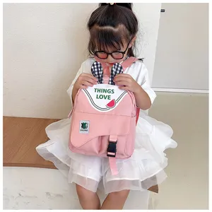 Detail view of cute pink children backpack featuring black white plaid rabbit ears and letters.