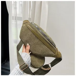 Detalle de bolso de pecho de pana verde oliva con cremallera, correa ajustable y monedero redondo.
