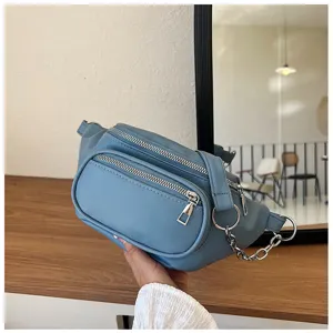 Close-up view of the blue casual waist bag, highlighting multi-zipper and metallic chain details.