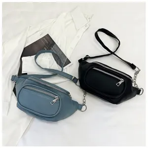 Detail shot of casual PU leather fanny pack with double zippers and metal chain decoration.