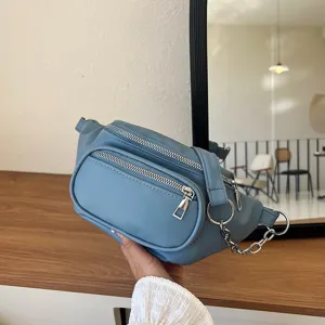 Women casual solid color blue waist bag crossbody bag with multiple zippers and chain.