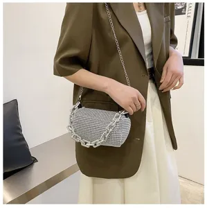 Close-up view of a sparkling rhinestone cylindrical handbag featuring a chunky metal chain strap.