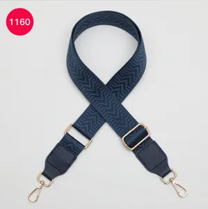 Close-up detail of navy blue woven bag strap with adjustable gold hardware and leather ends.