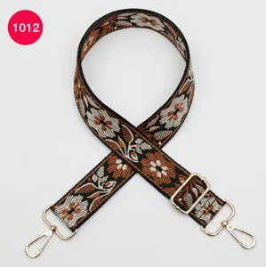 Detailed view of ethnic style jacquard wide bag strap with floral pattern and gold hardware.