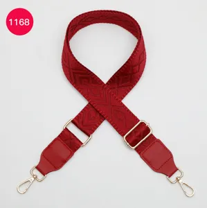 Détail de sangle de sac jacquard rouge avec texture tissée et accessoires dorés.