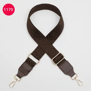 Gros plan de la bandoulière marron tissée avec un motif jacquard géométrique et des pièces en métal.