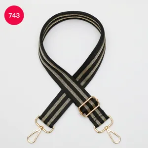Detailed view of the black and gold adjustable wide bag strap with metal buckles.