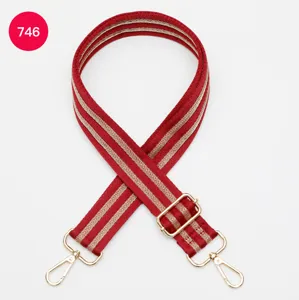 Detailed view of the red and gold striped adjustable replacement bag strap with gold metal hardware.