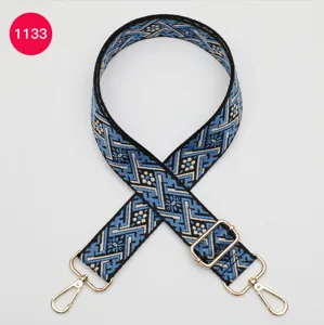 Vue détaillée d'une bandoulière de sac tissée jacquard bleu et noir avec accessoires métalliques.