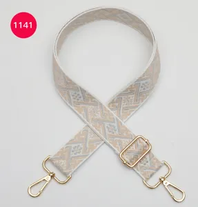 Détail de sangle de sac en jacquard, bandoulière tissée réglable avec boucles dorées.