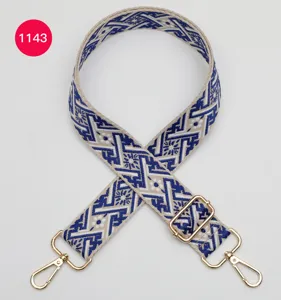 Bandoulière de sac ajustable avec motif jacquard géométrique bleu et boucles métalliques dorées.